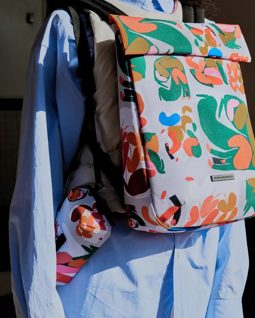 Backpack and pouch from Amber Vittoria’s exclusive UCON Acrobatics collection, featuring her signature abstract, colorful shapes in green, orange, pink, and gold on a white background